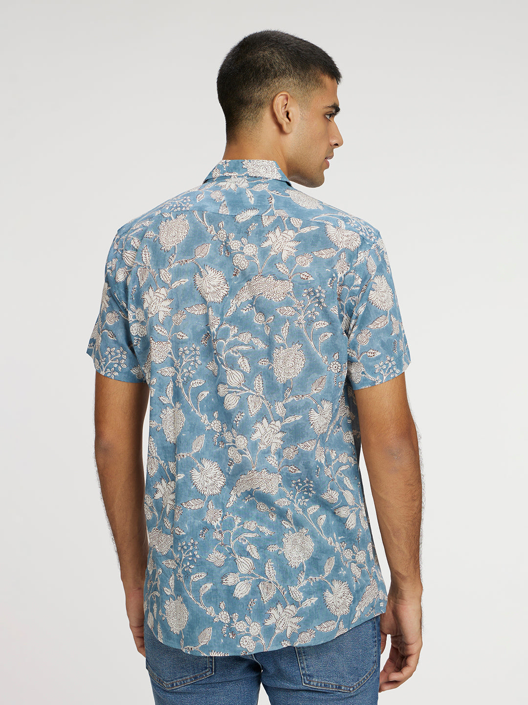 Model facing backwards wearing Blue Floral Block Printed Holiday Halfsleeves Mulmul Cotton Shirt by Brand Patrah