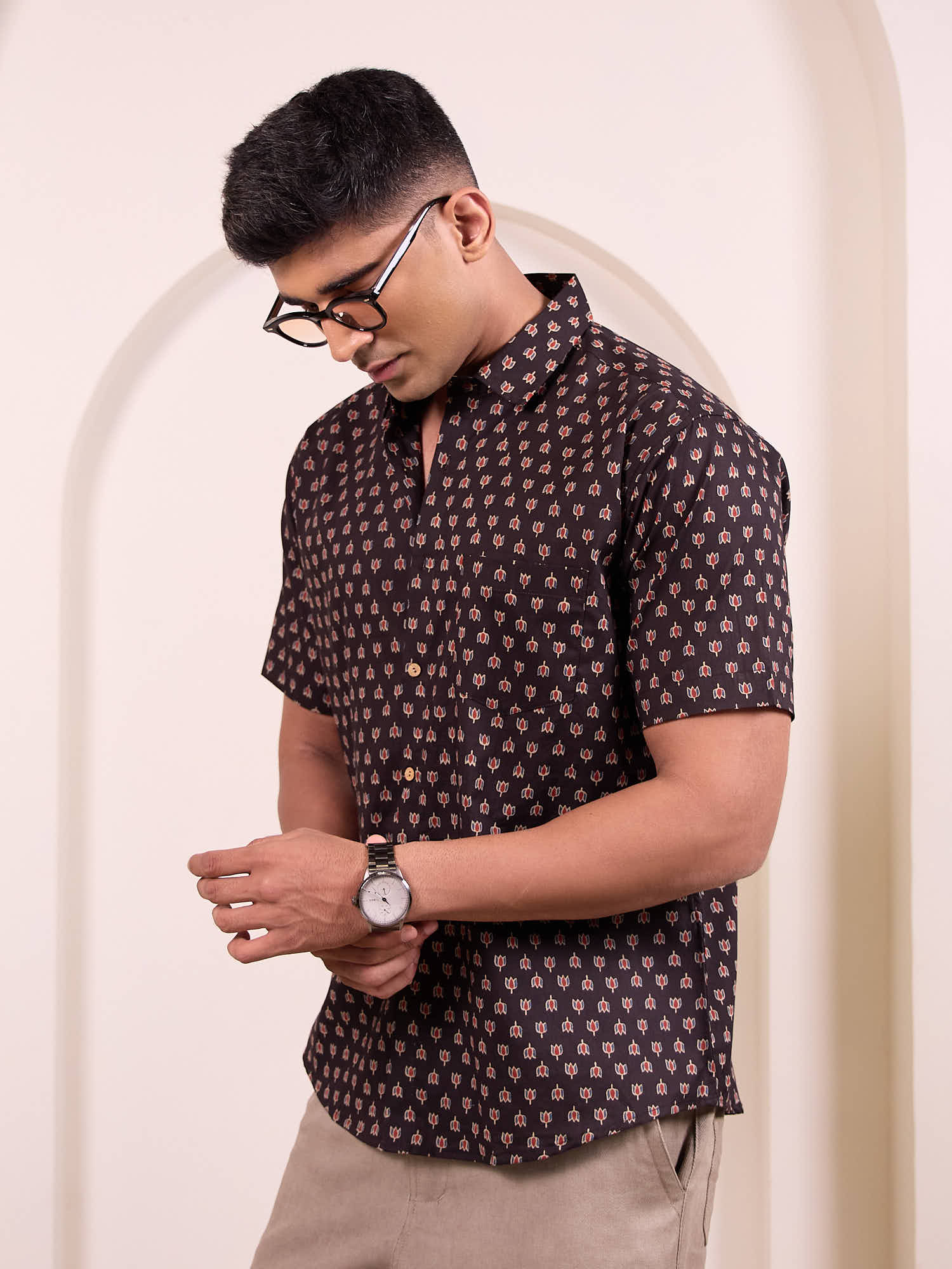 Man wearing a patterned shirt and glasses against a neutral background