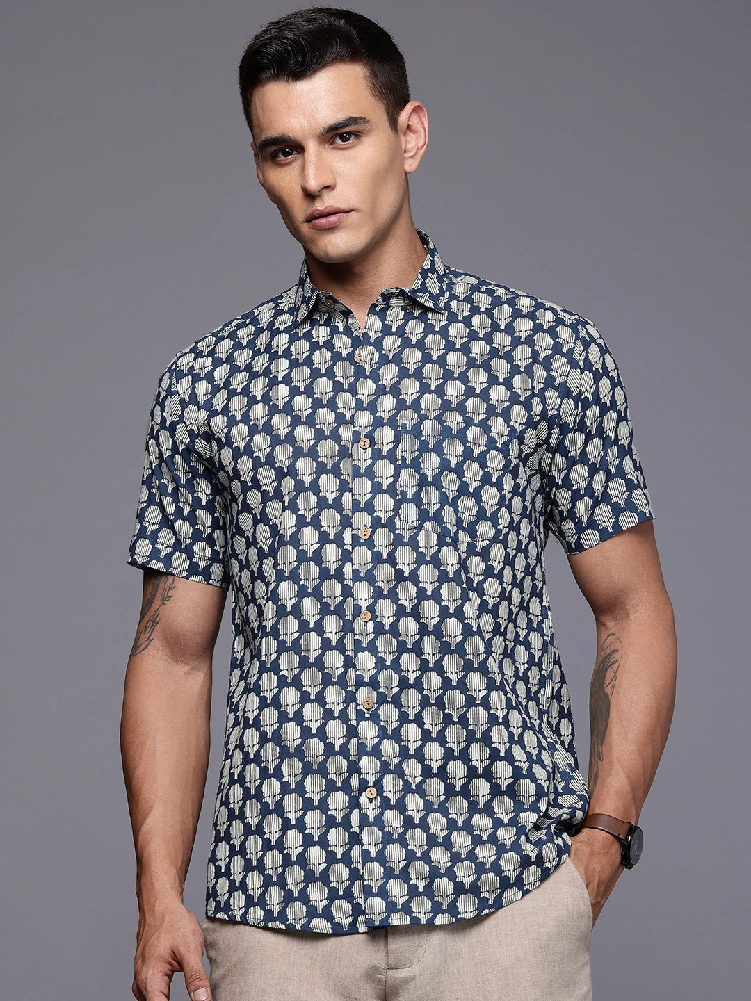 Man wearing a blue patterned shirt against a gray background