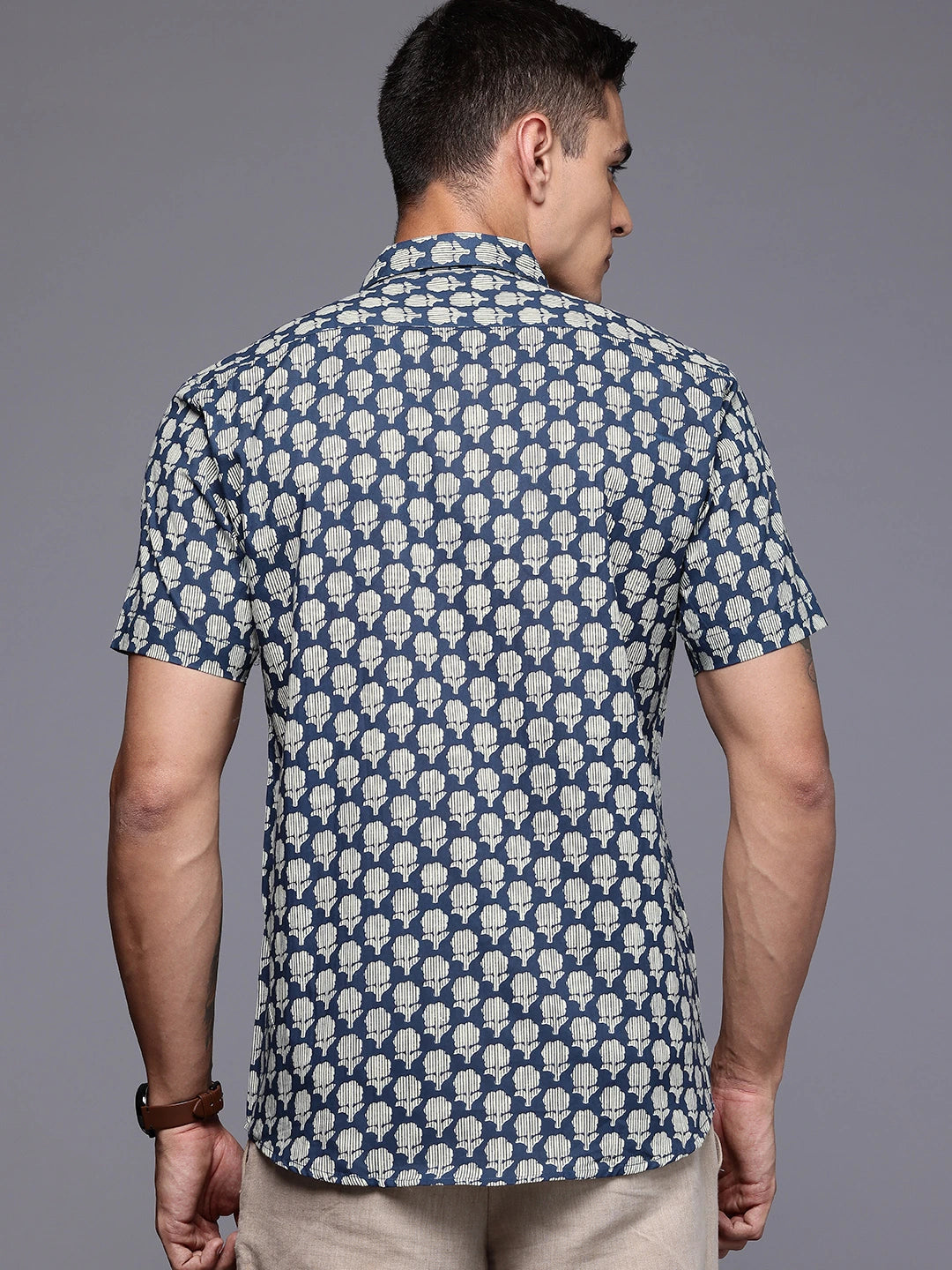 Man wearing a blue patterned shirt on a gray background