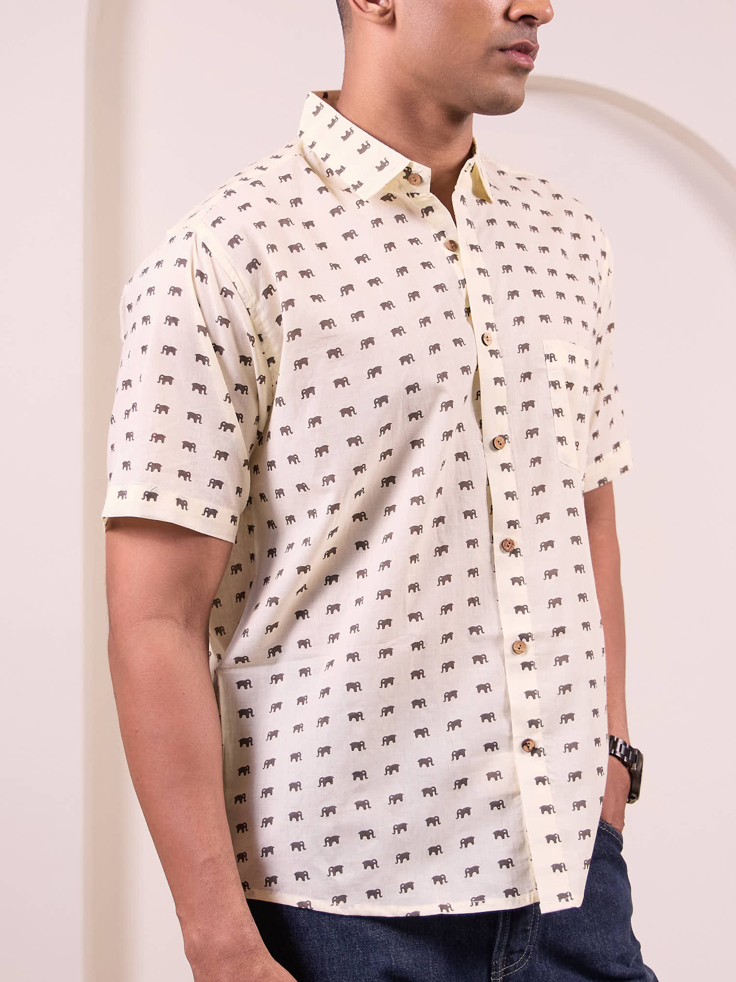 Man wearing a cream short-sleeve shirt with elephant pattern against a plain background