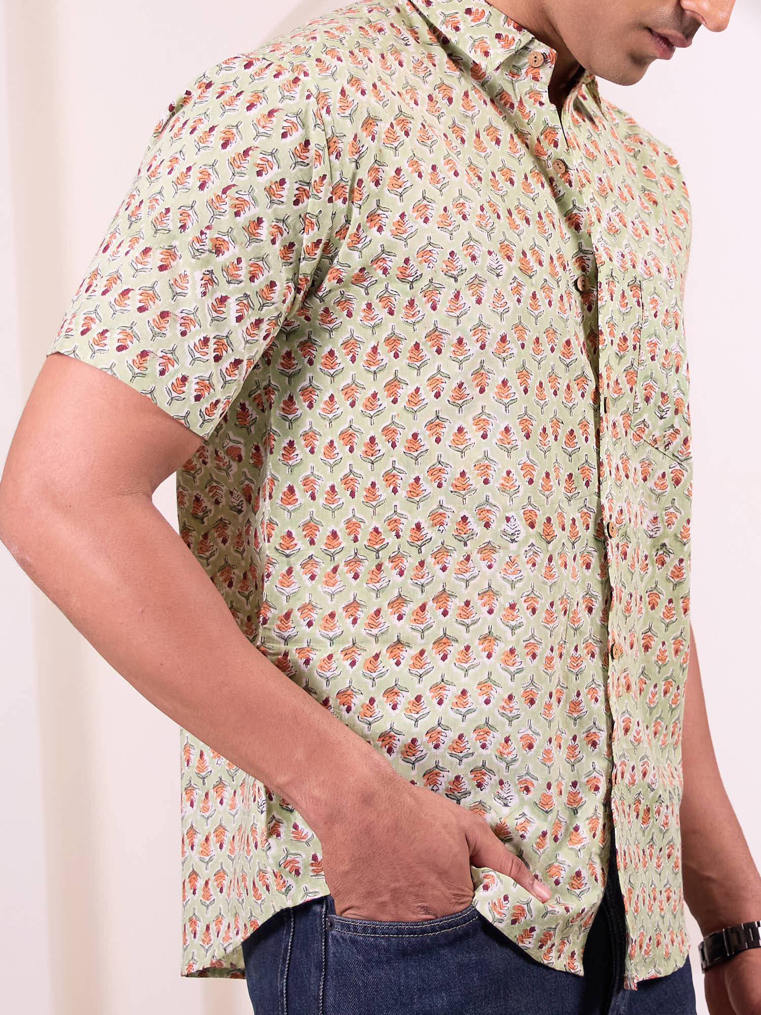 Model wearing a short-sleeve shirt with a floral pattern on a plain background