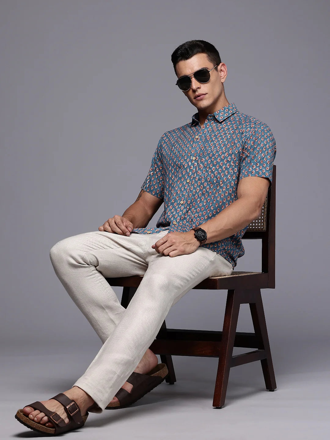 Man sitting on a chair wearing a floral casual shirt