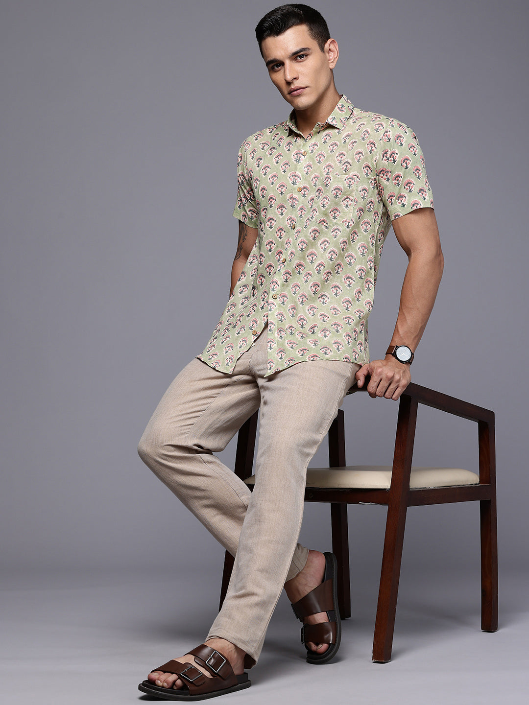 Man sitting on a chair wearing a green floral casual shirt
