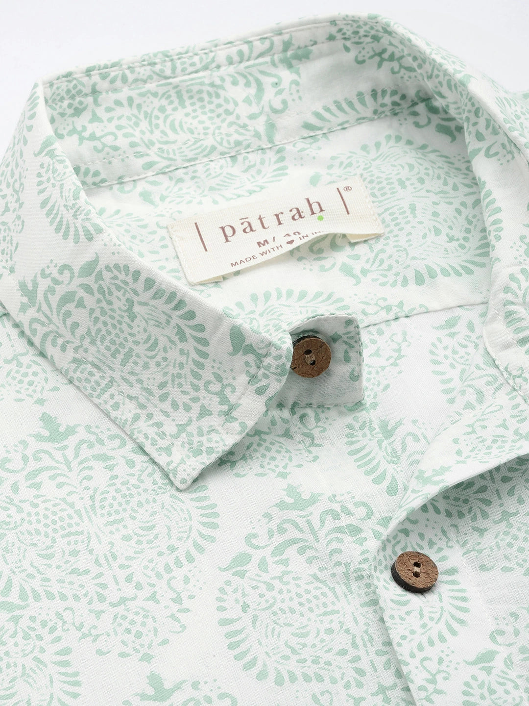 Green patterned shirt with patrah label on a white background