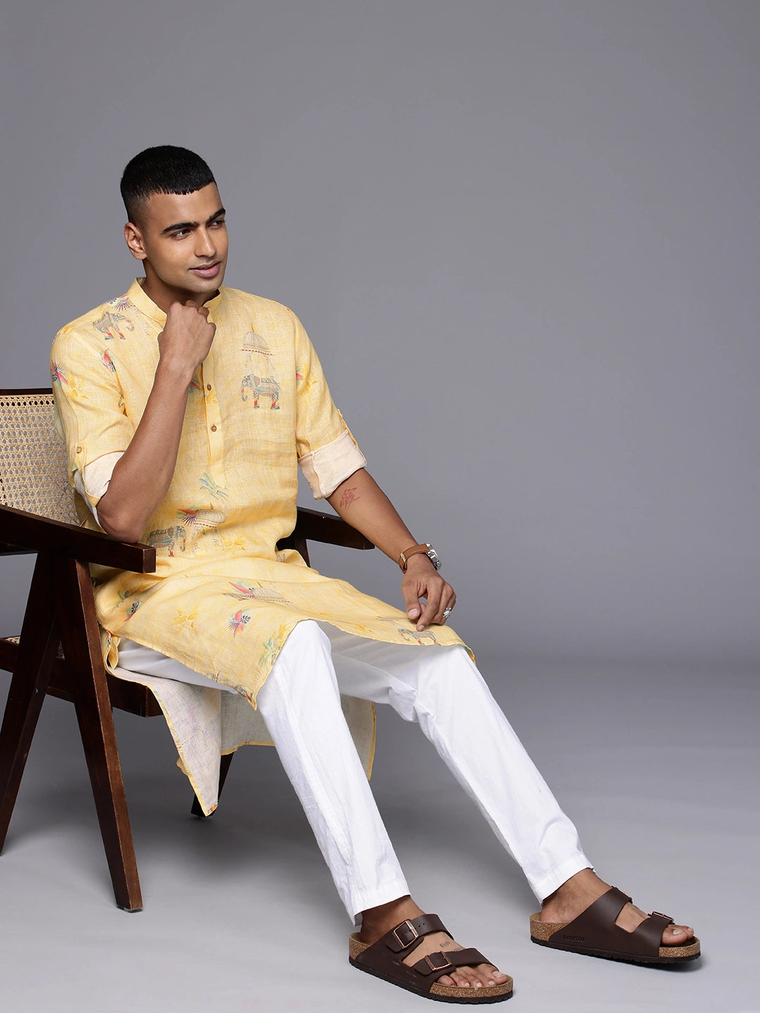 Black Model sitting on a chair wearing Yellow Elephant Print linen Kurta by Brand Patrah