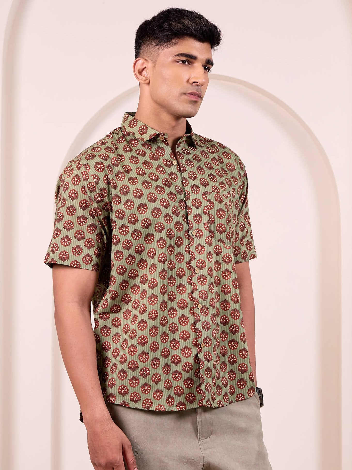 Man wearing a green patterned shirt against a beige background